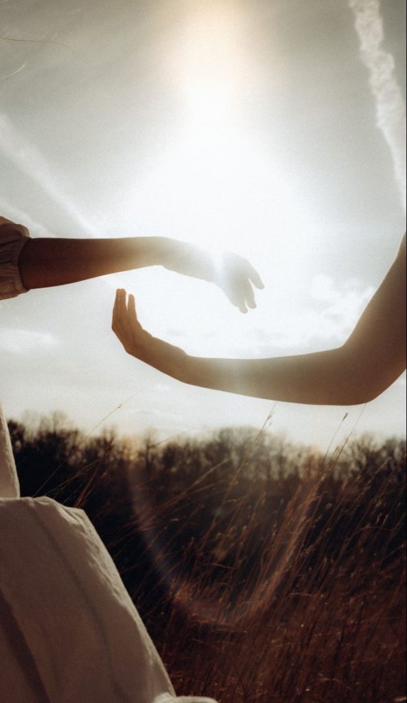 Manos extendidas hacia la luz